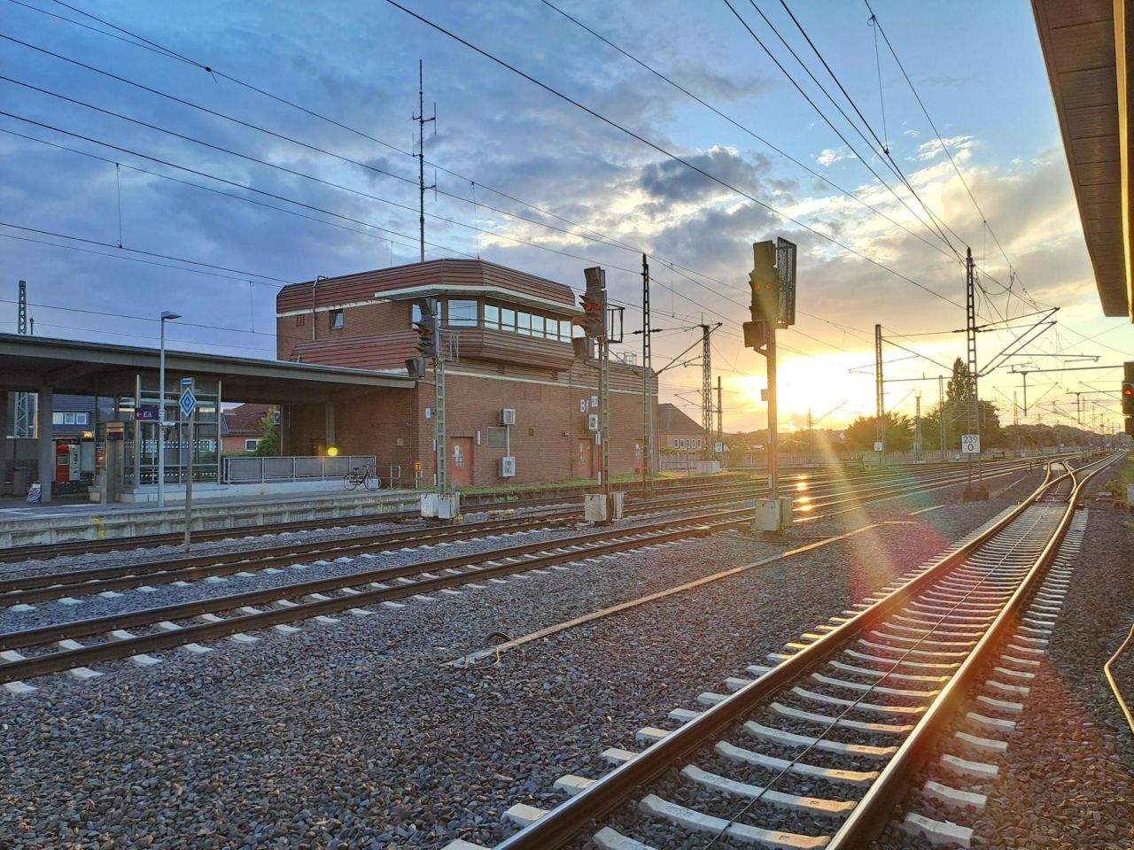 Bahnhof mit Stellwerksgebäude und Signalleuchte bei Sonnenaufgang