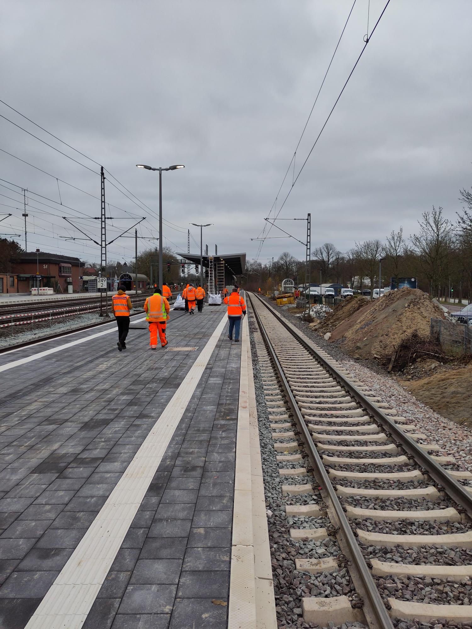 Mittelbahnsteig am Bahnhof Schwarzenbek, zu sehen sind Mitarbeiter der Baufirma in oranger Kleidung